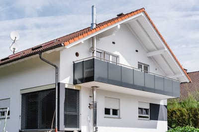 Glasgeländer mit Metallpfosten am Balkon eines Neubaus.