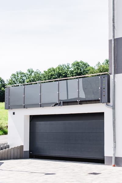 Getöntes Glasgeländer mit Edelstahlpfosten auf dem Balkon über einer Garage.